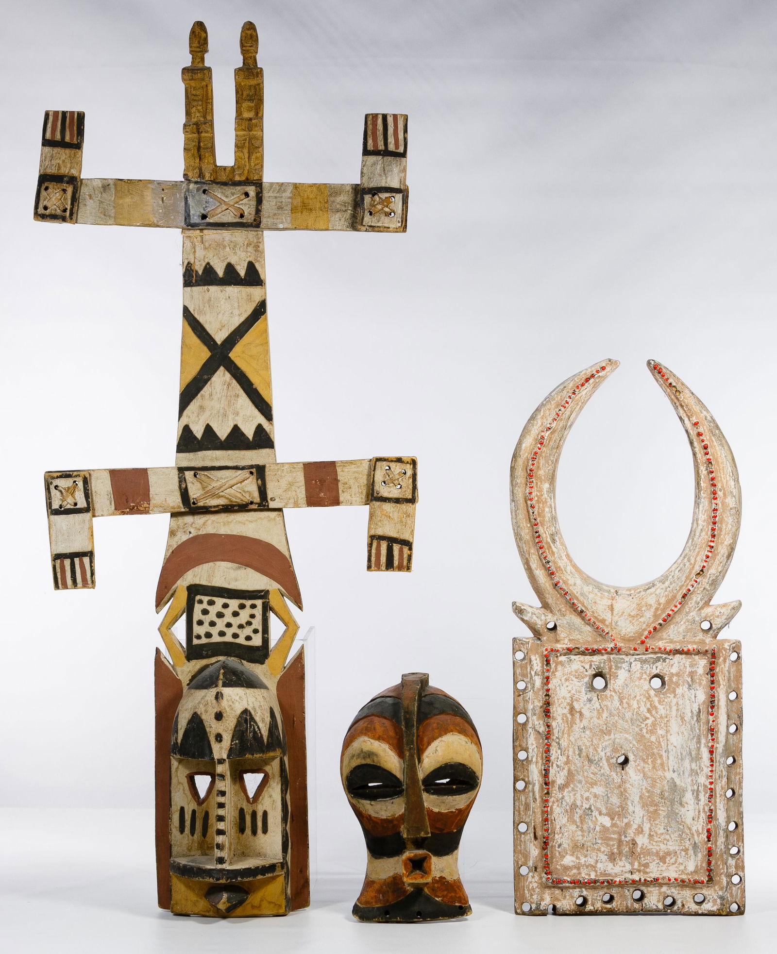 African Mask Assortment: African Mask Assortment Three items including a Kanaga face mask, a square mask having horns and glass bead accents as well as a painted primitive figure mask Condition: Very Good, overall moderate we