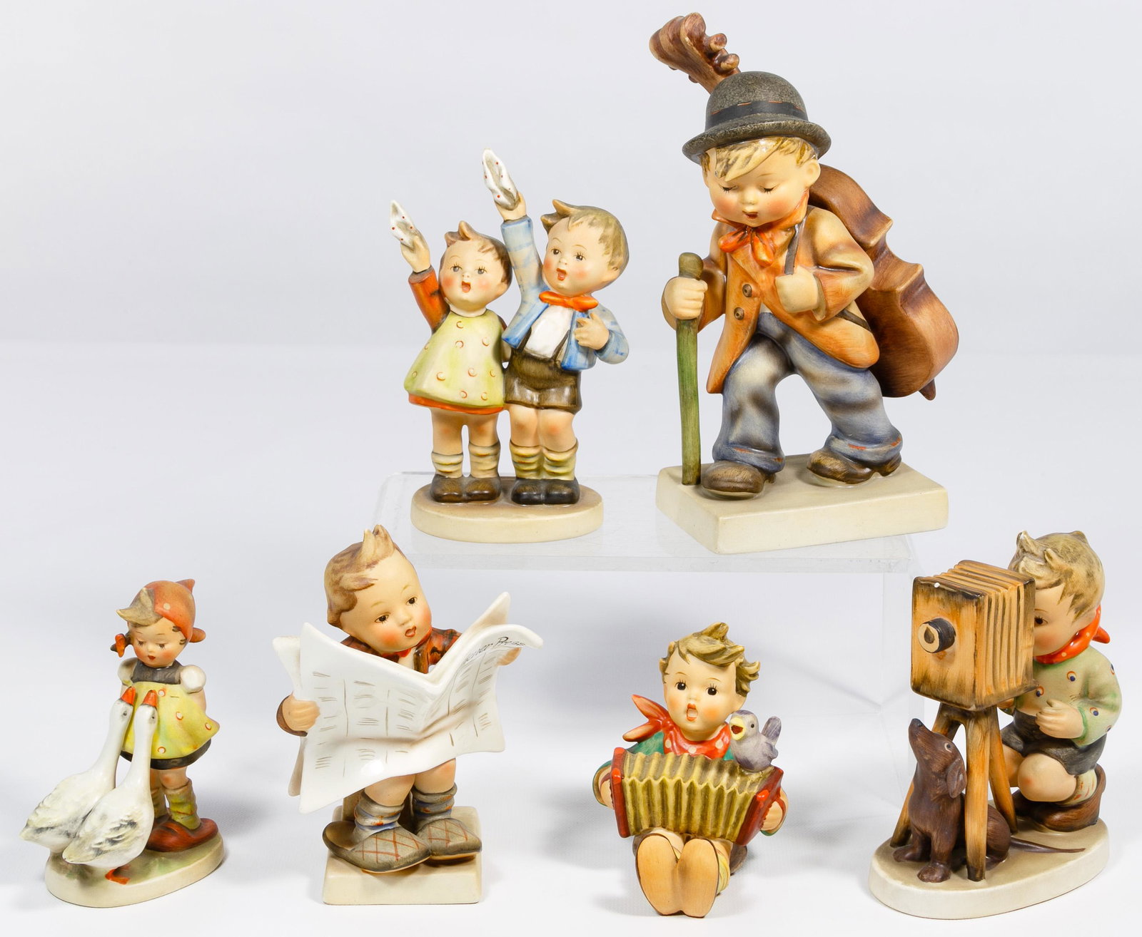 Hummel Figurine Assortment: Hummel Figurine Assortment Six items with five having TMK2 (1950-1955) hallmarks including #89/2 'The Cellist', #178 'The Photographer', #184 'Latest News', #153/0 'Auf Wiedersehen', #43 7/0 'Goose Gi