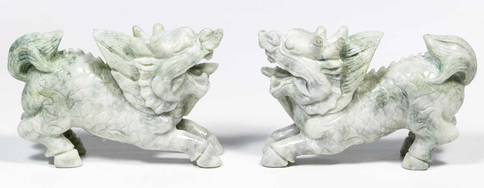 Chinese Jadeite Jade Lion Carvings: Chinese Jadeite Jade Lion Carvings Pair, grey and light green in color Condition: Good, overall light wear consistent with age and normal use; teeth on both chipped; gemstone(s) tested on the heat con