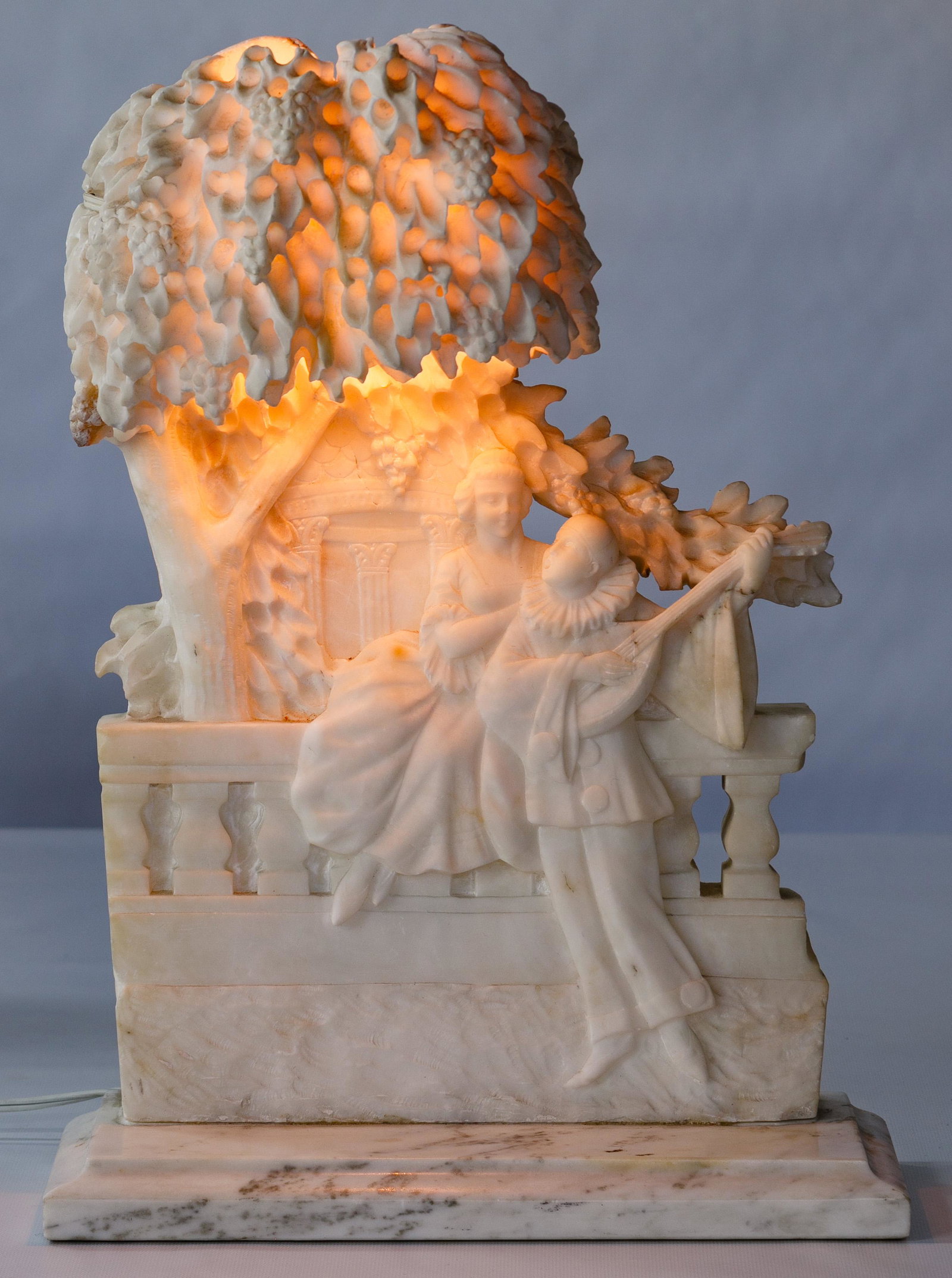 O. Rossi (Italian, 20th Century) Marble and Alabaster: O. Rossi (Italian, 20th Century) Marble and Alabaster Lamp Undated, signed en verso, depicting a harlequin playing the banjo next to a seated woman under a tree Condition: Very Good, repaired cracks d