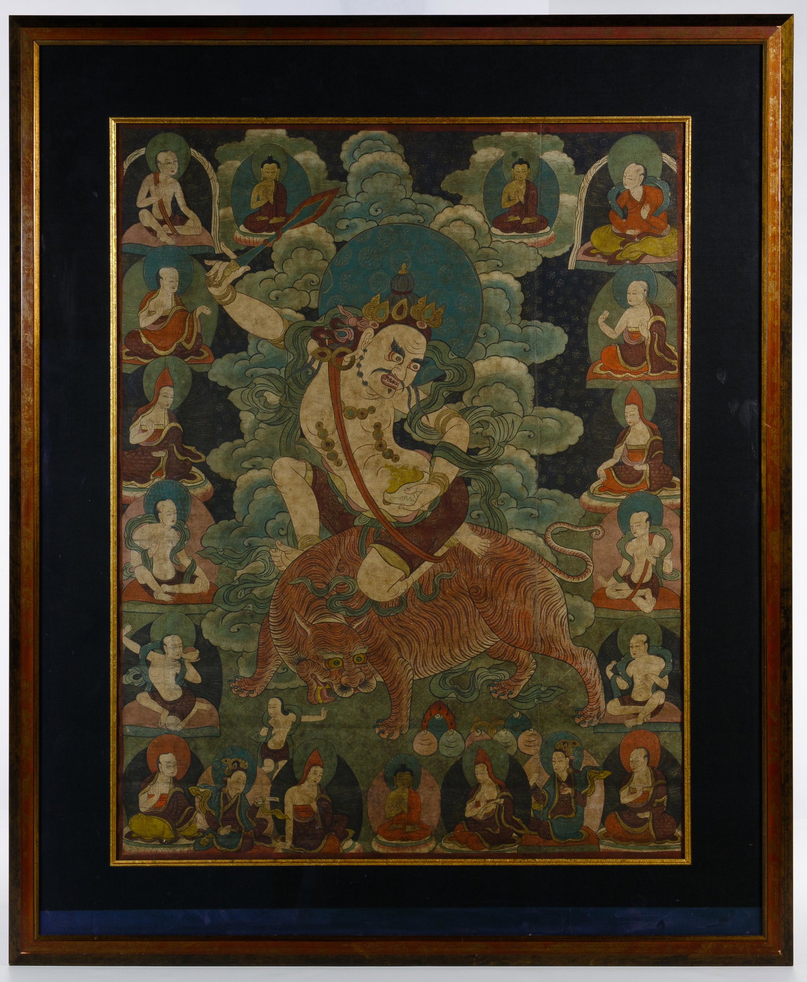 Asian Guardian Thangka: Asian Guardian Thangka Depicting Padma, a guardian Buddhist figure, riding a tiger Condition: Good, overall moderate wear consistent with age, creases, paint fading, buckling in frame, light dirt accu