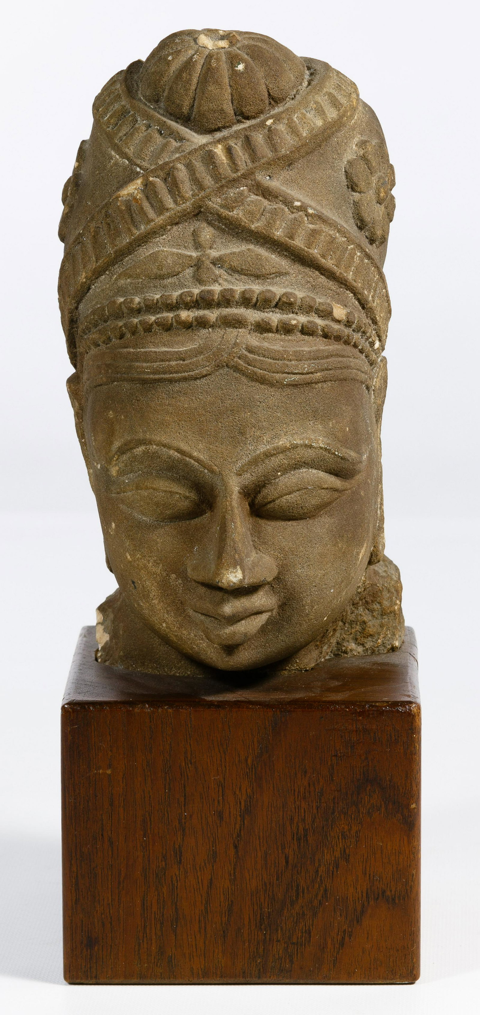 South Asian Sandstone Female Head: South Asian Sandstone Female Head 9th/10th century style, Hindu architectural fragment from North Central India, carved from a light colored sandstone, brown patina together with a wooden stand Condit