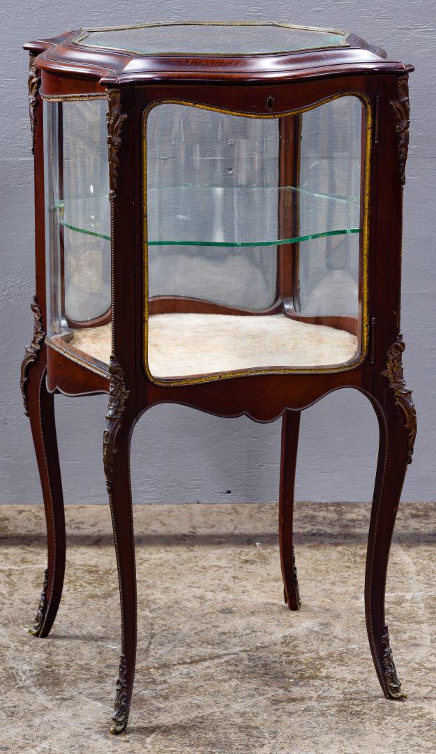 French Mahogany and Glass Vitrine: French Mahogany and Glass Vitrine Having four sides of curved glass bordered with metal trim, door at front with key, a glass shelf inside, metal trim on legs and feet Condition: Good, overall light w