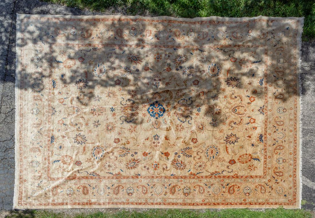 Persian Ushak Wool Rug: Persian Ushak Wool Rug Pakistan, having a cream background and hues of blue and orange, flower and paisley motif Condition: Good, overall moderate wear consistent with age and normal use, some fading 