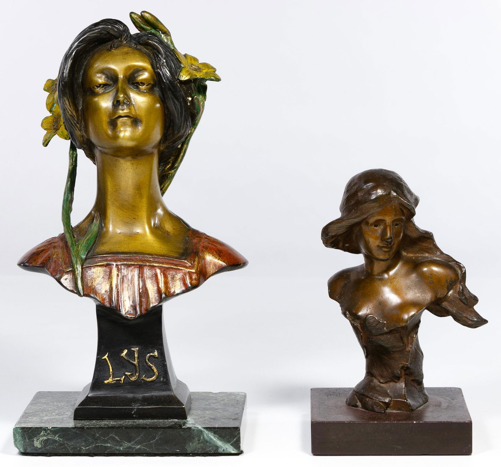 Female Bust Bronze Statues: Female Bust Bronze Statues Two items including a polychrome woman donning a wreath of flowers marked 'LYS' on front and mounted on a marble plinth; and a long haired monochrome woman partially wrapped
