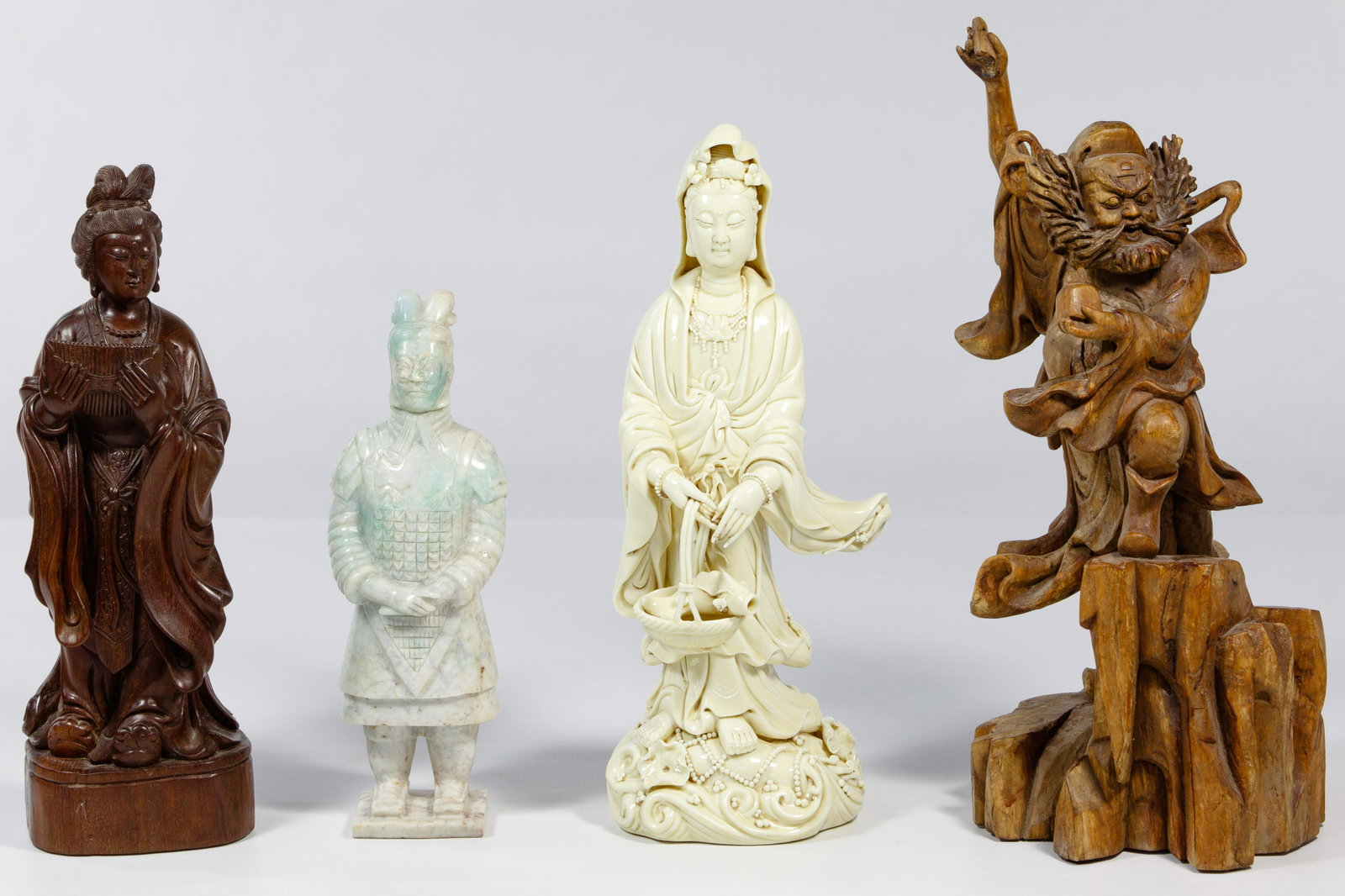 Chinese Figurine Assortment: Chinese Figurine Assortment Four items including a pale green ice jadeite jade Qin style warrior, a boxwood guardian figure, a Blanc de Chine Guan Yin having double gourd and square seal marks on reve