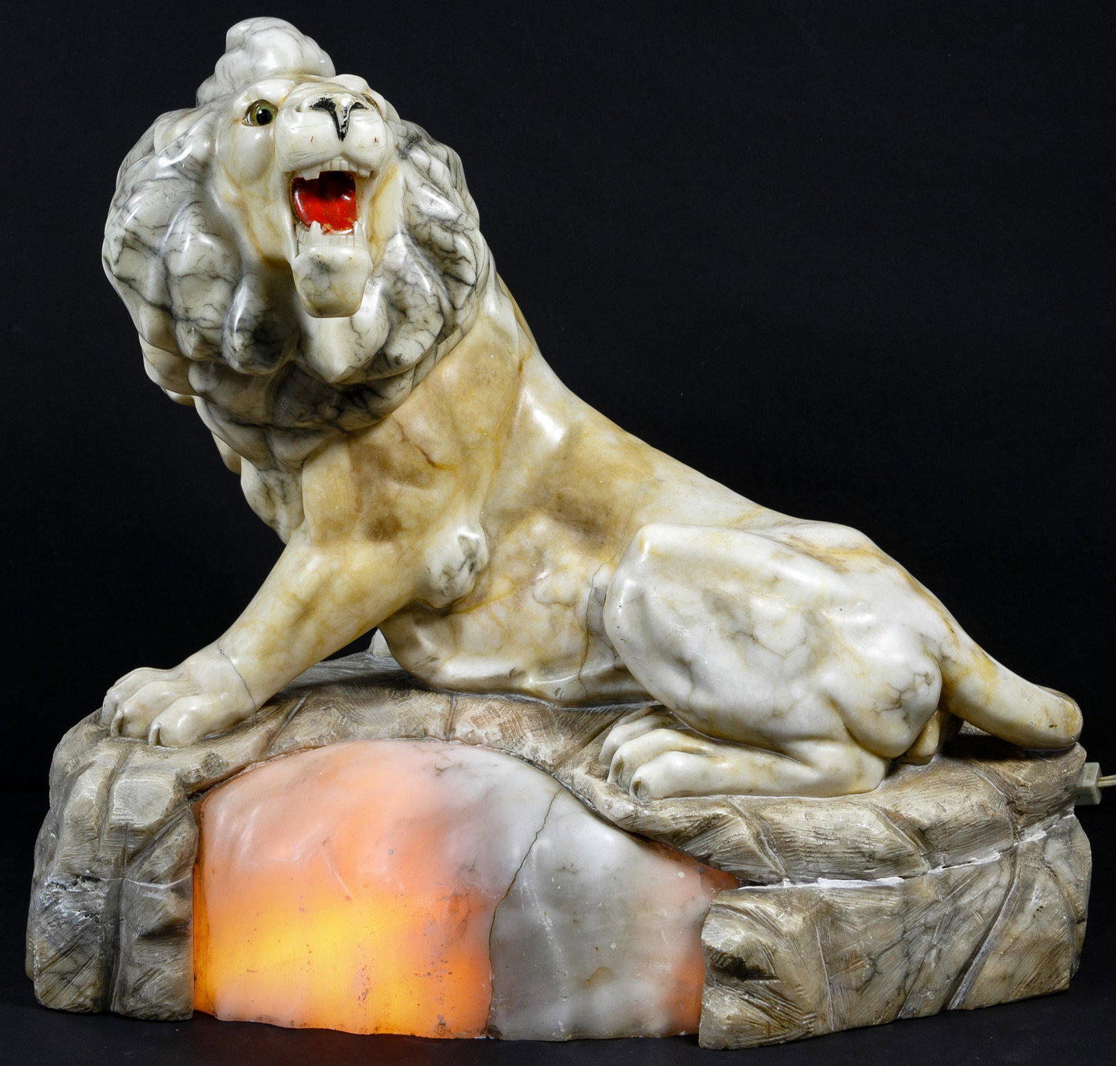 Alabaster Lion Accent Lamp: Alabaster Lion Accent Lamp Depicting a roaring lion atop a rock, having grey and brown veining, painted mouth and nose, glass eyes and a lamp socket on underside to illuminate the rock; property from 