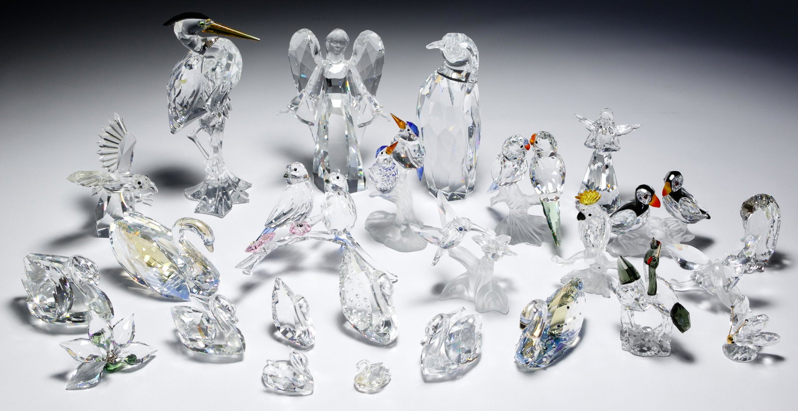 Swarovski Crystal Bird Assortment: Swarovski Crystal Bird Assortment (25) items including having the Swarovski mark (9) swans in varying sizes, (2) penguin figurines, (5) polychrome bird figurines, (2) angels, (2) butterflies and a flo