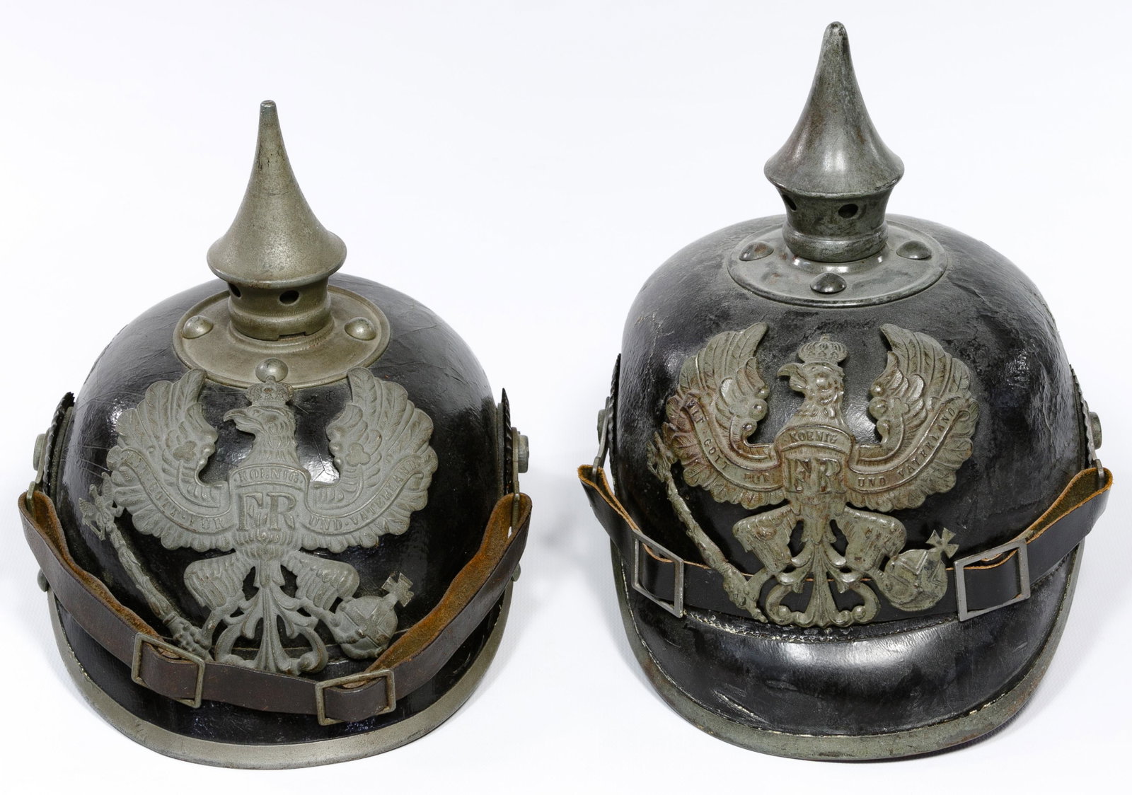 World War I Pickelhaube Helmets: World War I Pickelhaube Helmets (2) items including a Prussian enlisted man's black leather body with gray metal accessories and leather chinstrap; and Prussian enlisted man's infantry black leather b