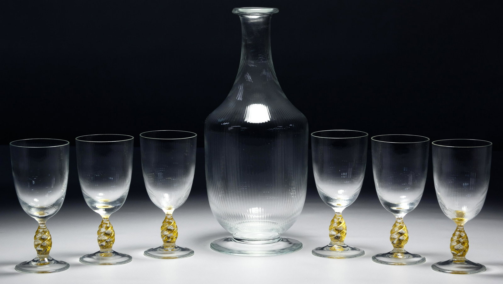 Murano Gold Fleck Wine Glass and Decanter Collection: Murano Gold Fleck Wine Glass and Decanter Collection (8) items including (7) hand blown wine glasses (vino fino) having a ribbed bowl on a twisted baluster stem and a ribbed clear carafe (bottiglia); 