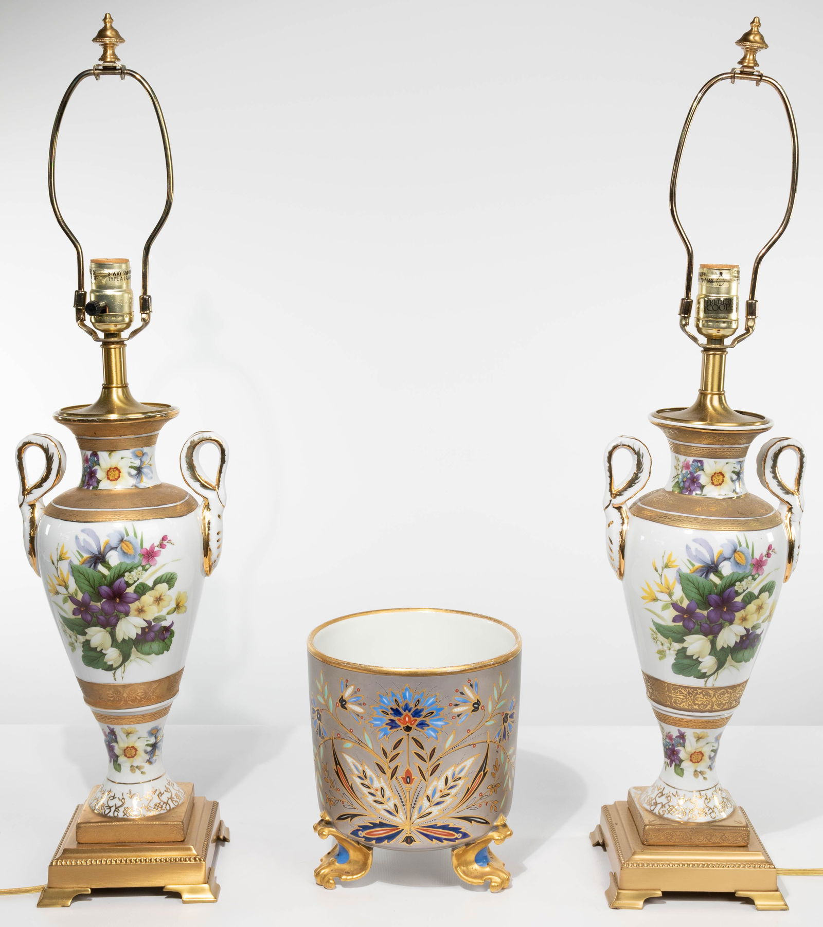 Frederick Cooper Porcelain Table Lamps: Frederick Cooper Porcelain Table Lamps Pair of urn style lamps having floral transfer and gilt decoration mounted atop a gold metal base, maker label on the socket; together with a cache pot having a