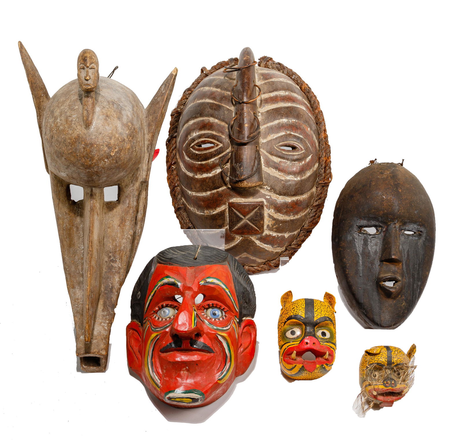 Multi-Cultural Carved Mask Assortment: Multi-Cultural Carved Mask Assortment (6) items including a Dogon tribal in the form of a devil / crocodile; a Luba oblong having almond-shaped eye slits, a long nose with 4 metal rings and an X mouth