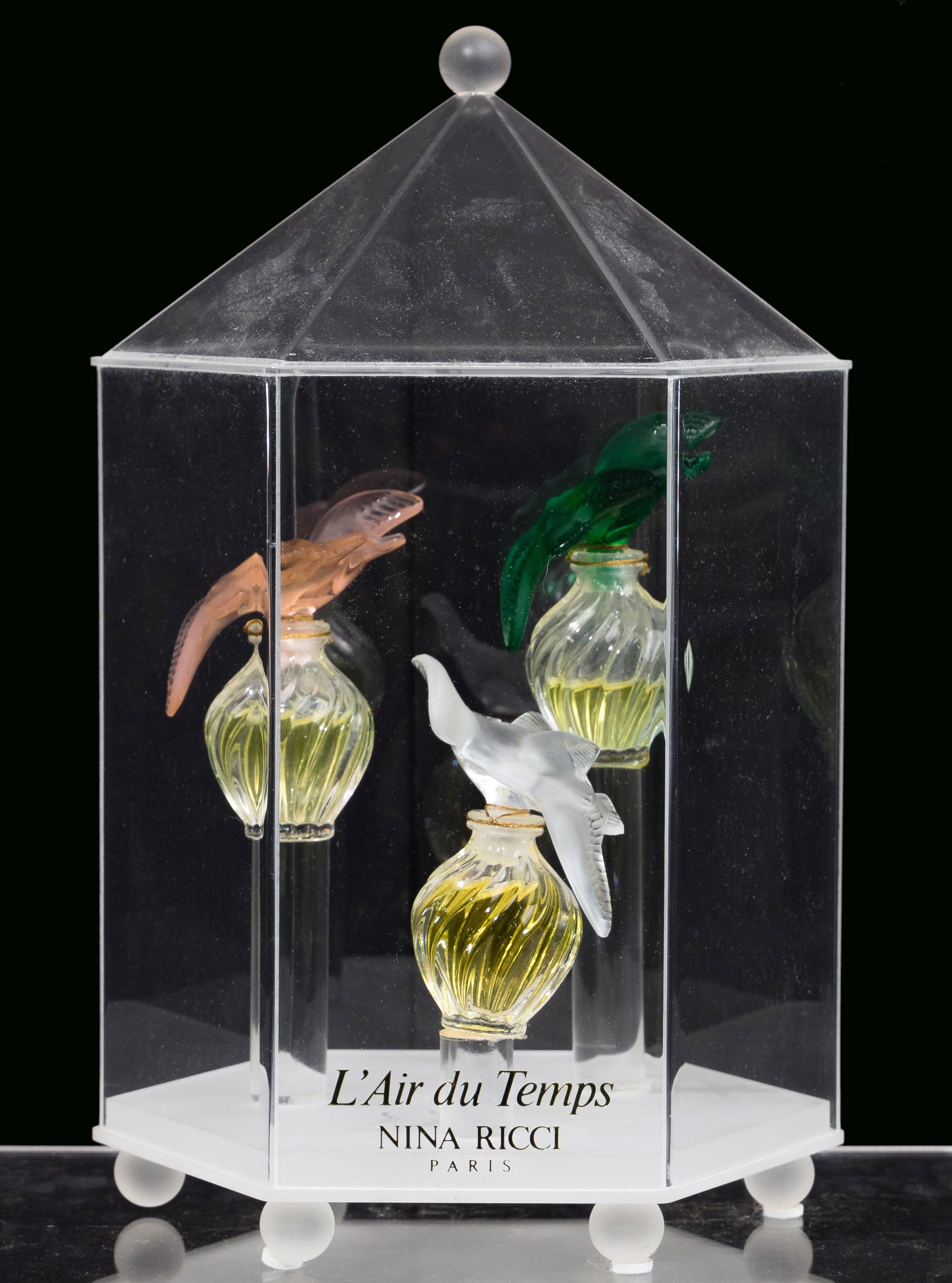 Lalique Crystal 'L'Air du Temps' Perfume Bottles and: Lalique Crystal 'L'Air du Temps' Perfume Bottles and Display (3) bottles having frosted dove tops in pink, green and clear; in a footed display having bottles on pedestals at varying heights and an ac