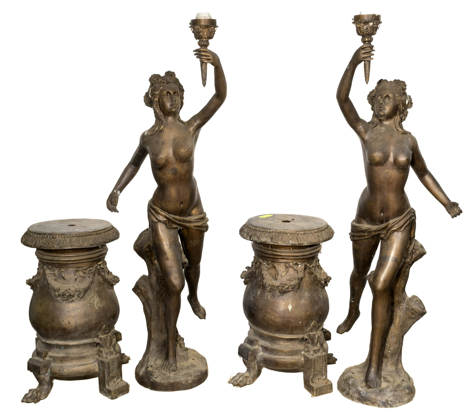 Cast Metal Figural Torchieres On Stands: Cast Metal Figural Torchieres On Stands Mirror pair of draped nude females standing beside stumps, a hand raised holding a torch with a socket, a foot back; on bases having laurel draping and alternat