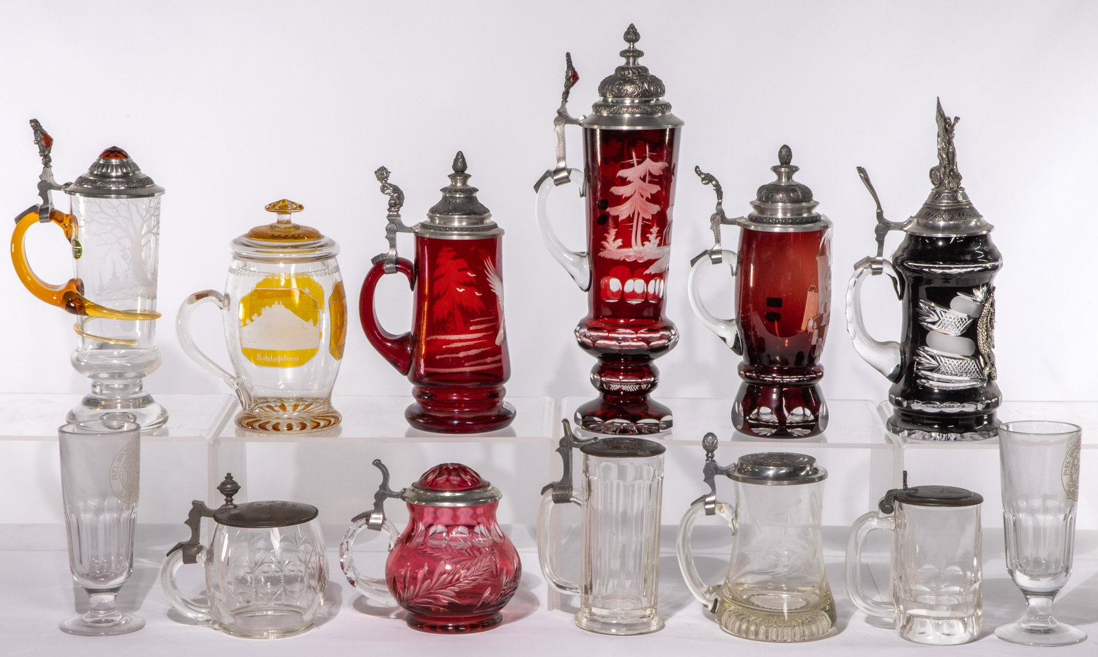 Glass Stein and Mug Assortment: Glass Stein and Mug Assortment (13) items including (5) steins and mug having red cut to clear decoration including flip-up metal / metal rimmed glass lid; (4) steins and mugs having clear glass inclu