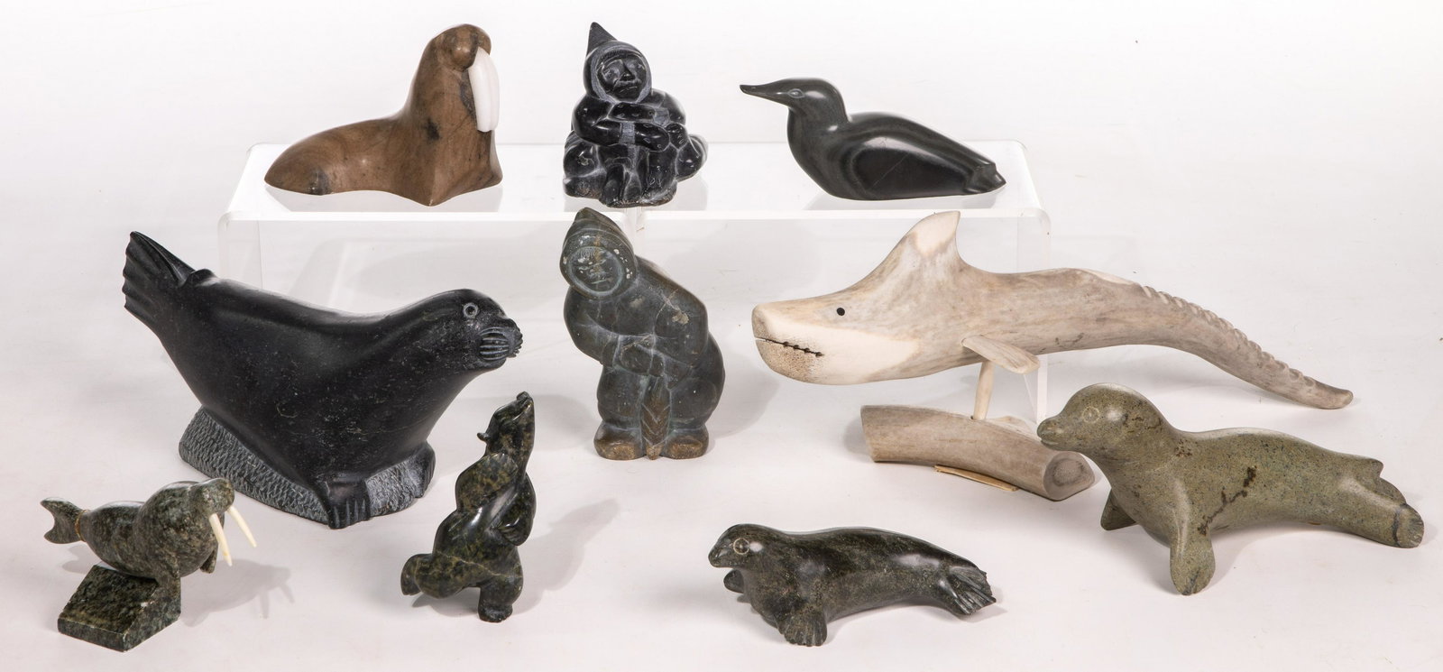 Inuit Carving Assortment: Inuit Carving Assortment (9) items including human figures, walrus, seals, a shore bird and a bear of soapstone, a fish including stand of bone; many illegibly signed on undersides, some retaining lab