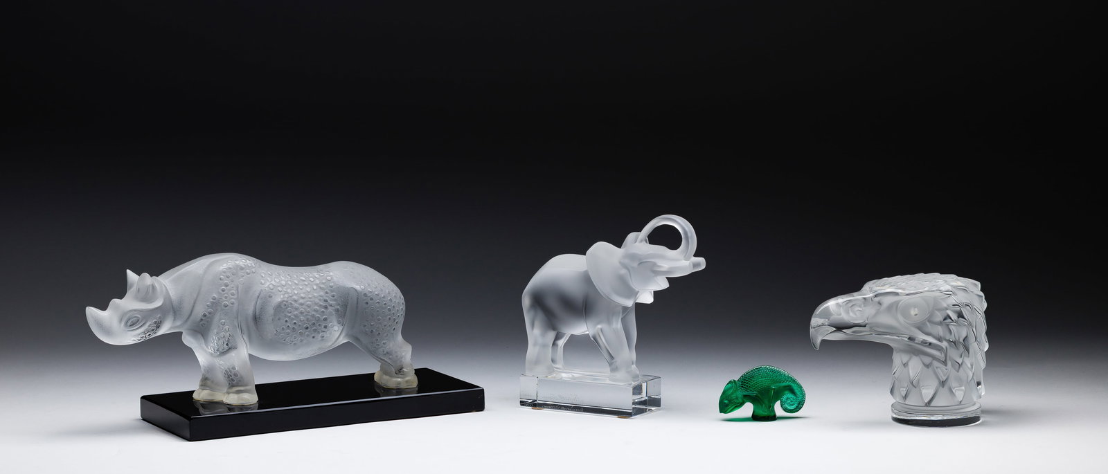 Lalique Crystal Assortment: Lalique Crystal Assortment (4) items including Tete d'Aigle and elephant paperweights as well as a Toba rhinoceros on a black hard stone base and a green chameleon, all marked Property from: a