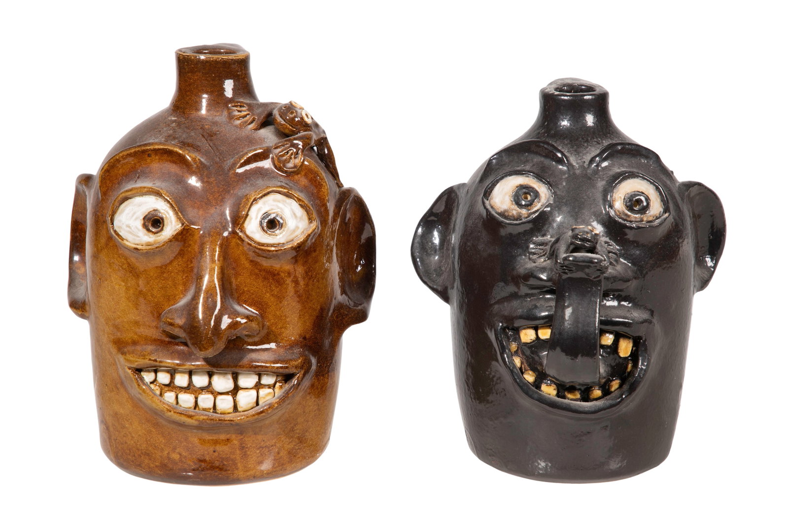 Robert Jackson Ugly Face Pottery Jugs: Robert Jackson Ugly Face Pottery Jugs (2) items, both glazed in hues of brown having incised signature underside and stamped Jackson Pottery mark to sides, painted details, both incorporating