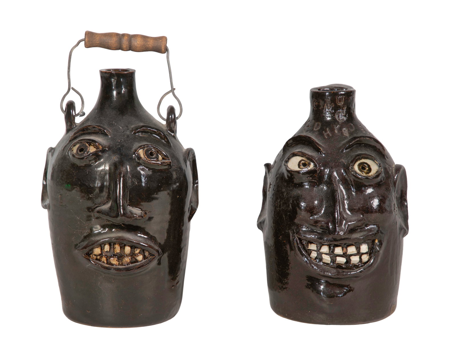 Robert Jackson Ugly Face Pottery Jugs: Robert Jackson Ugly Face Pottery Jugs (2) similar big mouth devil jugs, white kaolin clay for teeth / eyes, one having a wood handle, one incised using the alphabet Property from: an Estate, Glen Elly