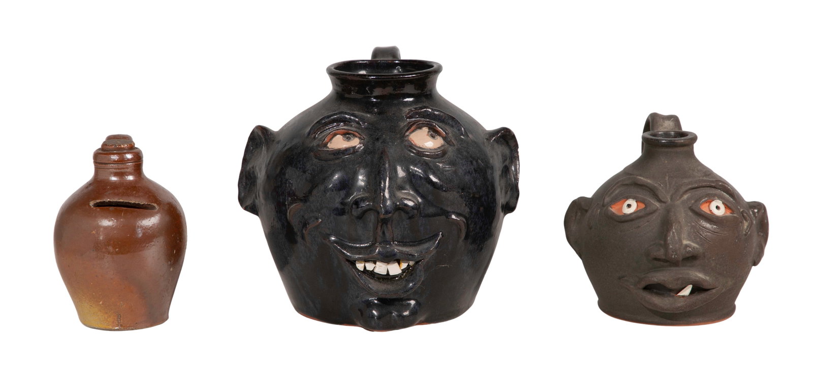 L. Lefton for Grey Willow Ugly Face Pottery Jugs: L. Lefton for Grey Willow Ugly Face Pottery Jugs (3) total items including (2) undated, signed jugs having white eyes and teeth, applied handles; together with a glazed stoneware bank in an ovoid