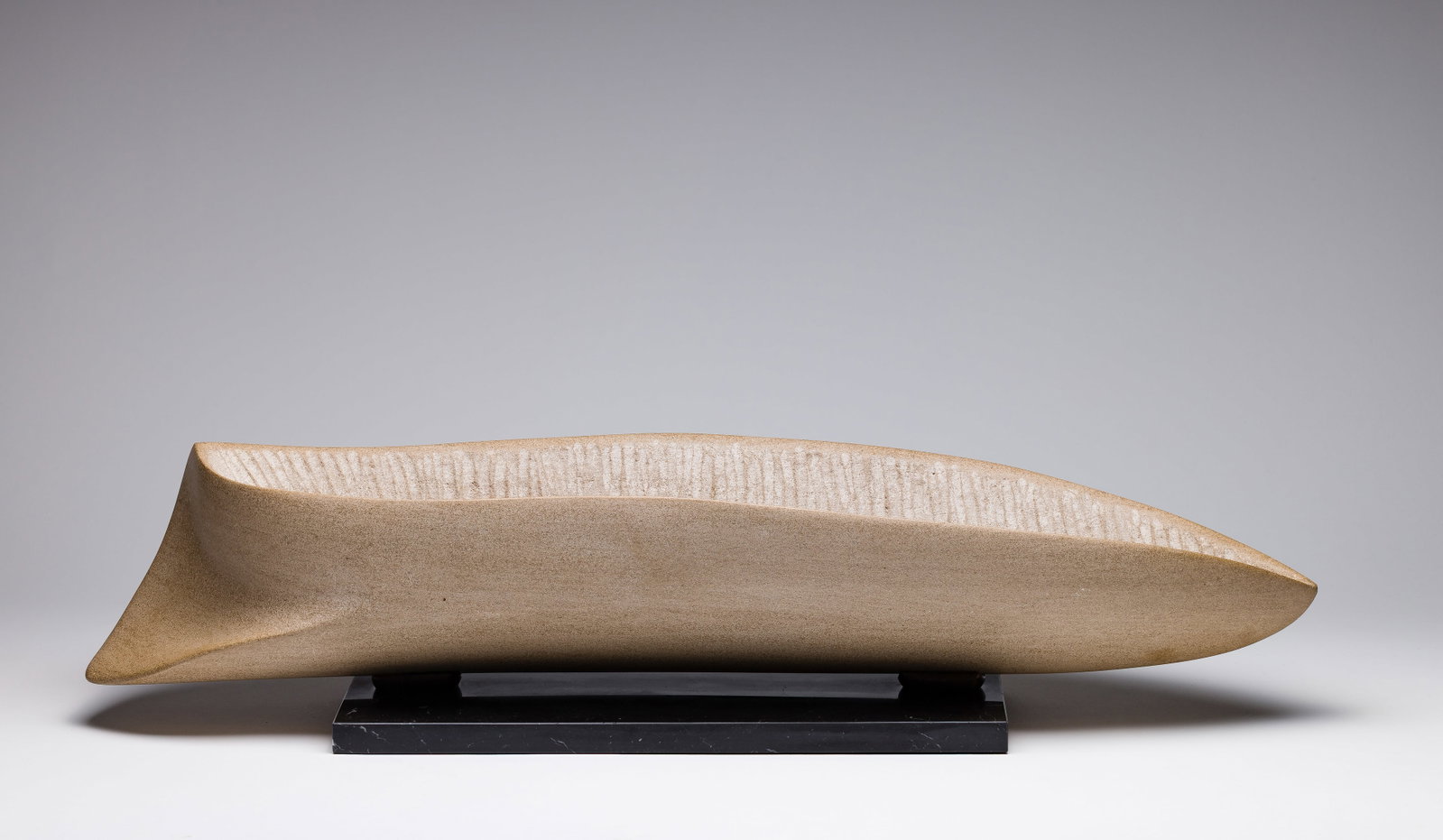 Beth Sahagian (American, 20th Century) 'Fossa II' Stone Sculpture: Beth Sahagian (American, 20th Century) 'Fossa II' Stone Sculpture Undated, engraved signature and title near keel of the canoe-shaped carving, custom marble display stand Property from: an Estate, Chi