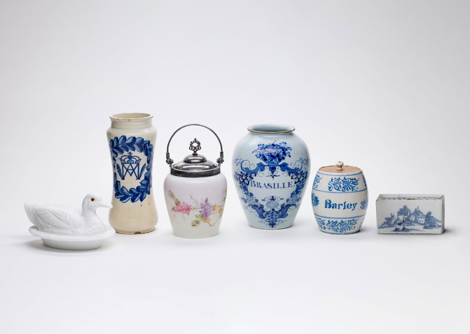 Stoneware and Glass Assortment: Stoneware and Glass Assortment (6) items including, in glass, a white duck-form covered dish and a floral jar with a silver lid and, in stoneware, a British delftware flower brick, a cream-colored vas