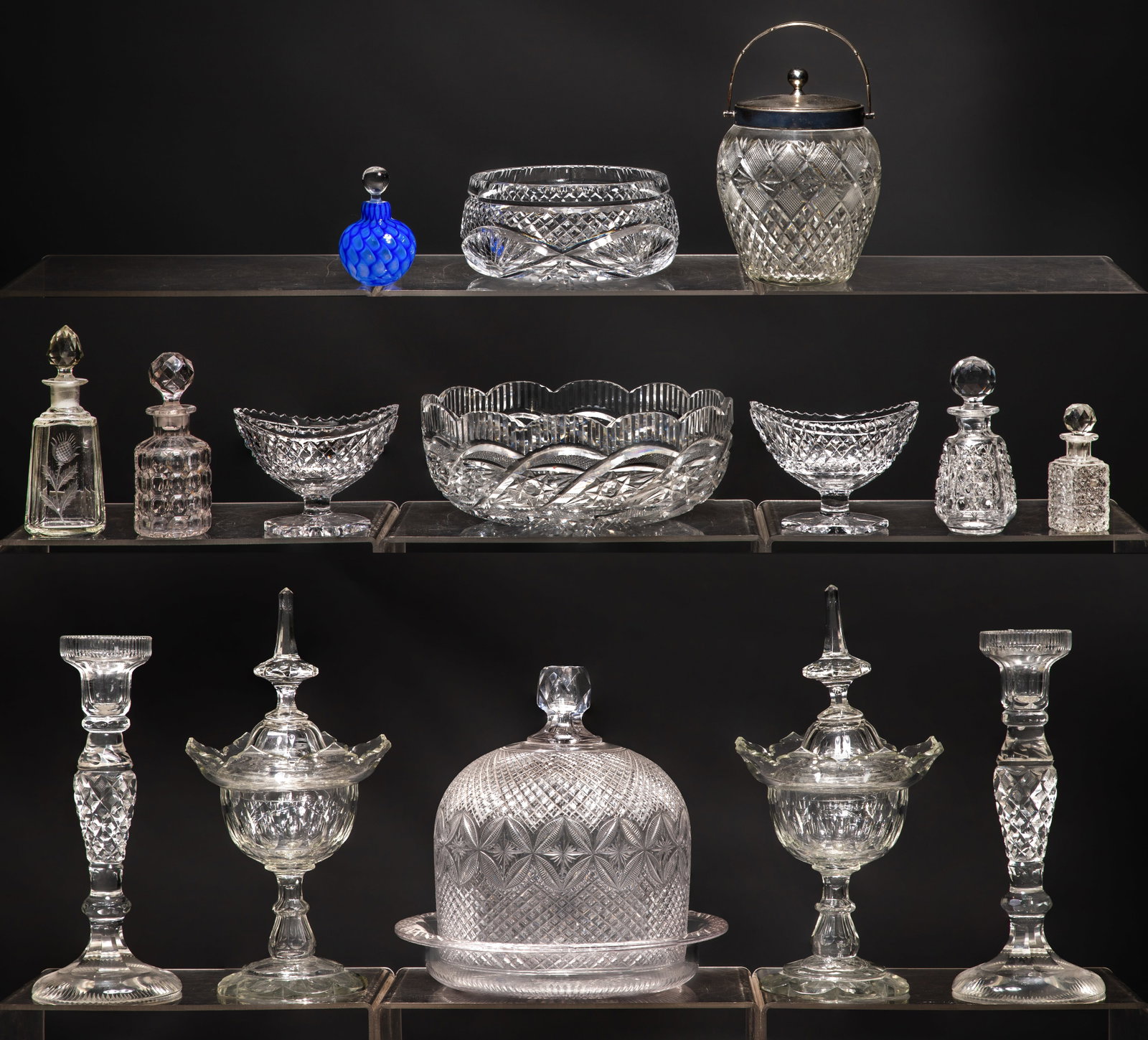 Cut Glass Assortment: Cut Glass Assortment (15) items including cut glassware and crystal tableware such as faceted decanters, geometric centerpiece bowls, cheese dome, candlesticks and cruets with stoppers Property from: