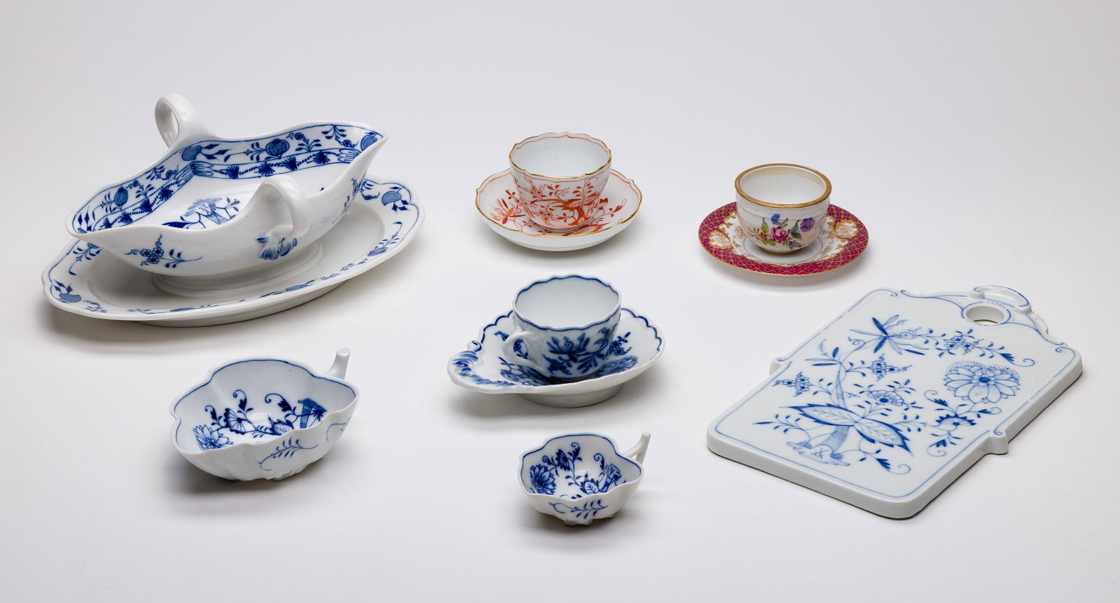 Meissen Porcelain Assortment: Meissen Porcelain Assortment (10) items including a gravy boat having attached underplate, a cheese board, (2) leaf shaped small cups, a vide poche and a demitasse cup having underglaze blue decoratio