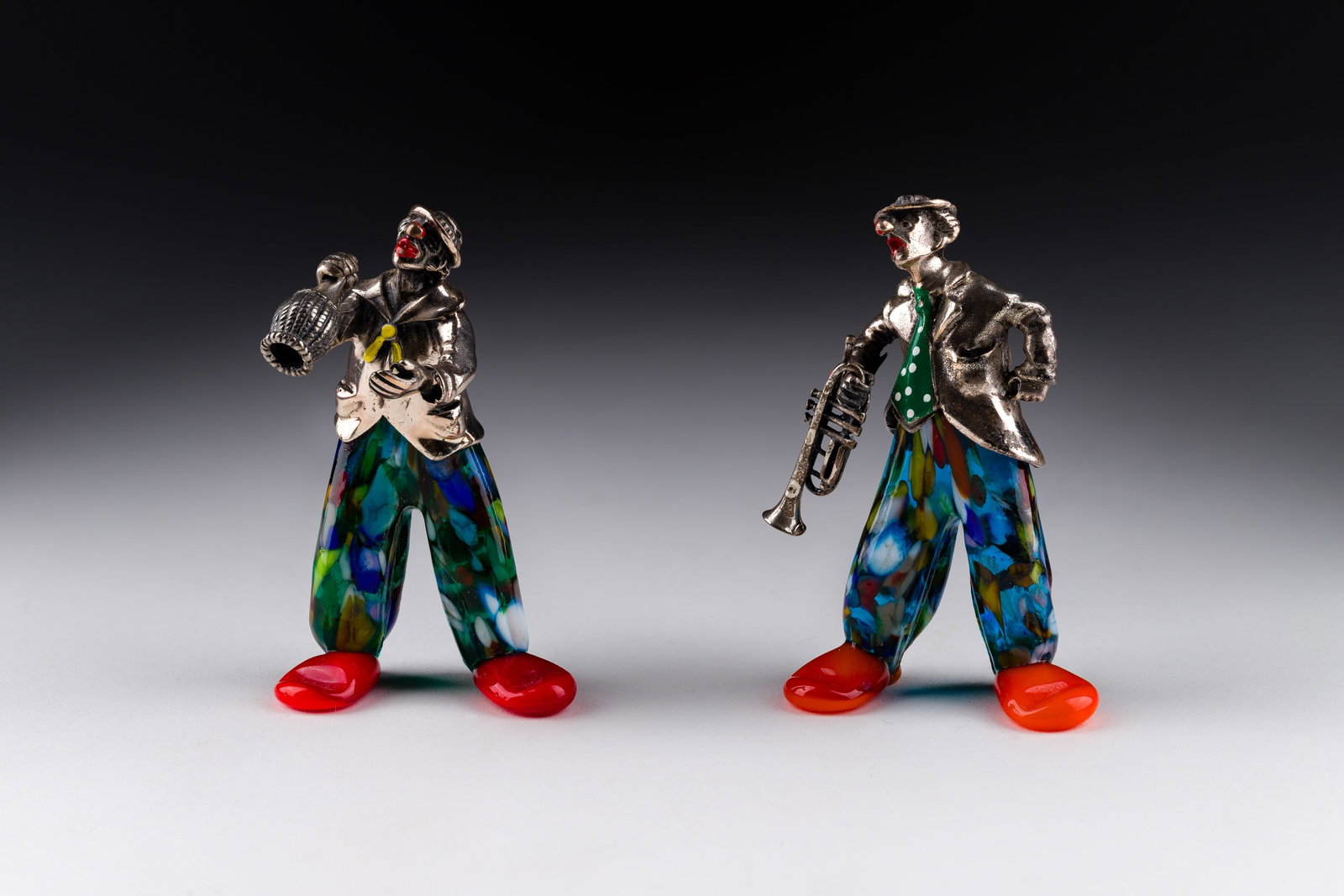 Vittorio Angini (Italian, 20th Century) Murano Glass and Silver Figurines: Vittorio Angini (Italian, 20th Century) Murano Glass and Silver Figurines (2) items having enamel on silver upper bodies on glass legs and feet including a reveler holding a wine bottle (unmarked 925)