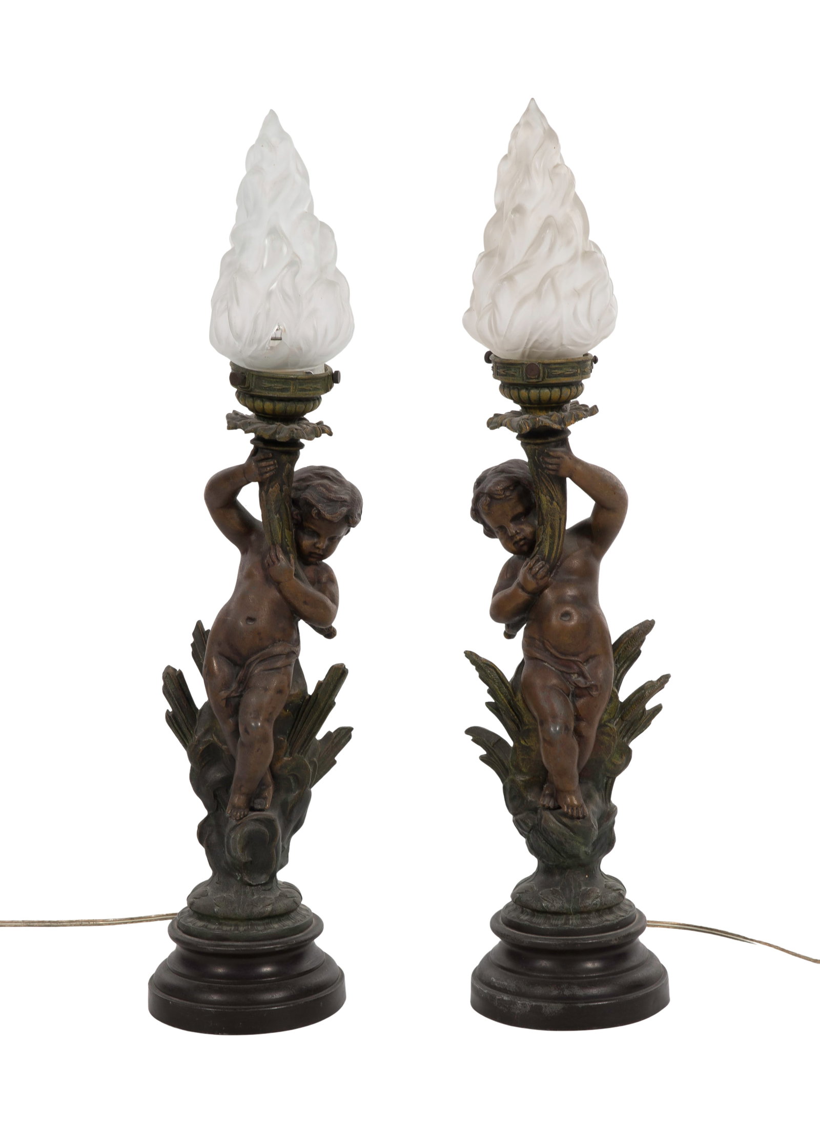 French Painted Putti Lamps: French Painted Putti Lamps A matched pair having a spelter base putti holding a torch, socket having a frosted glass flame form shade, marked France on backside Property from: a Private Collector,