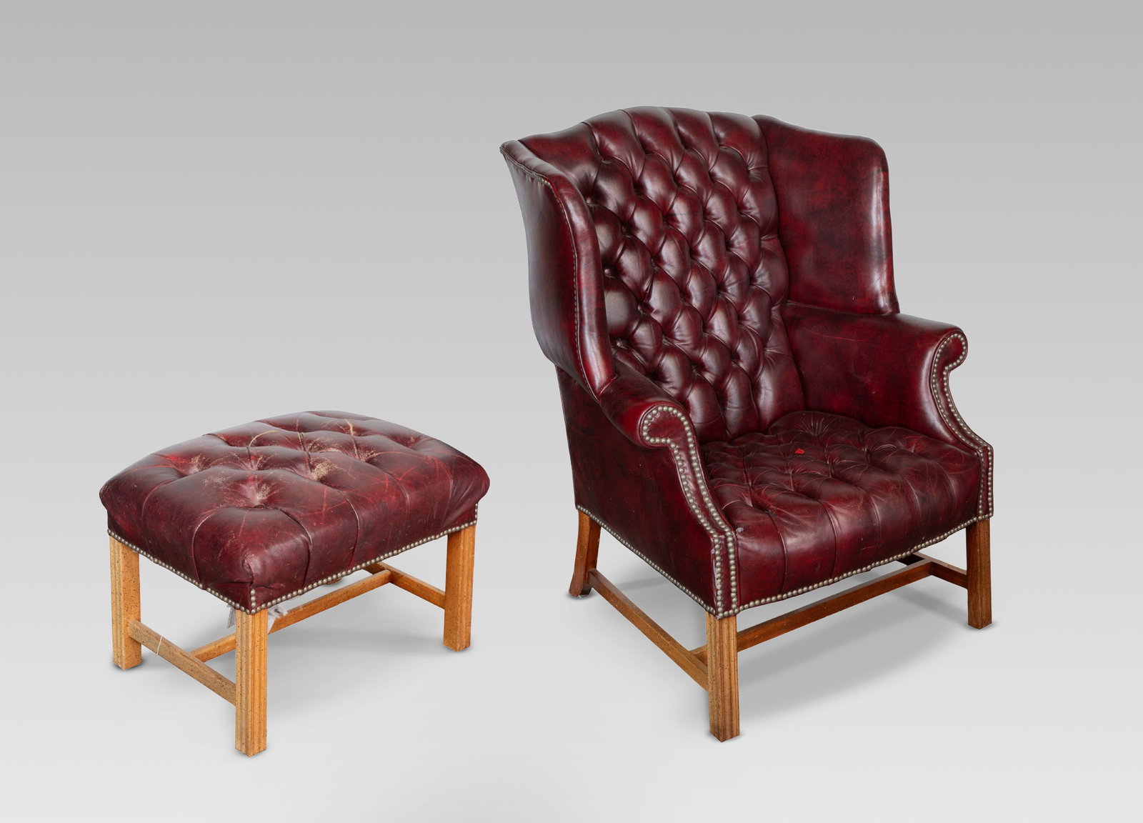 Tufted Leather Armchair and Ottoman: Tufted Leather Armchair and Ottoman (2) items including a wingback armchair and matching ottoman, both having oxblood red leather and nail head trim, wood having intentionally paint speckled finish,