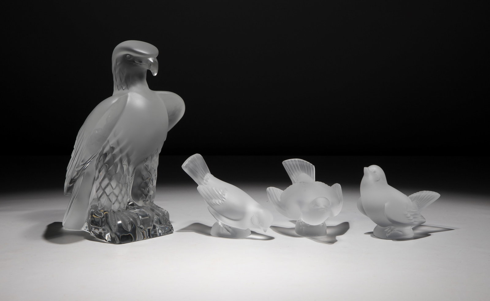 Lalique Crystal Bird Assortment: Lalique Crystal Bird Assortment (4) items including a Liberty Eagle sculpture having frosted body perched upon a clear, polished rock-form base and (3) Moineau (small sparrows) pecking, preening and