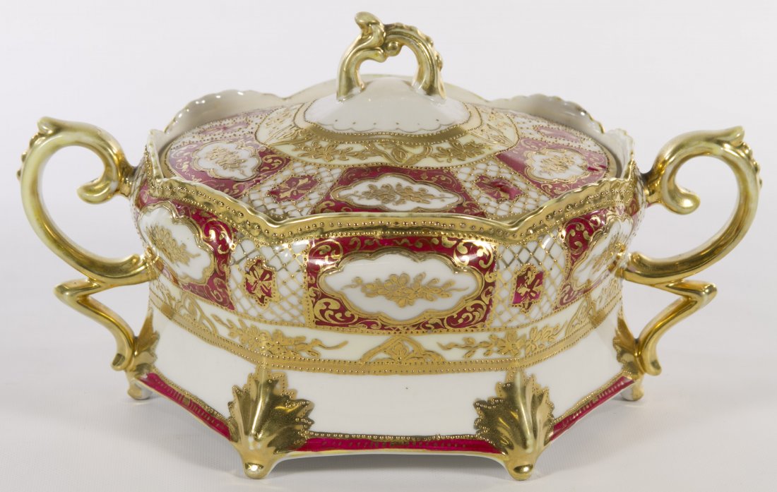 Nippon Porcelain Covered Dish: Nippon Porcelain Covered Dish c.1910; having a red and white ground, scrolled handles, moriage and gilded decoration; marked on the underside with a green maple leaf Height: 5.00 inches, Width: 9.00 i