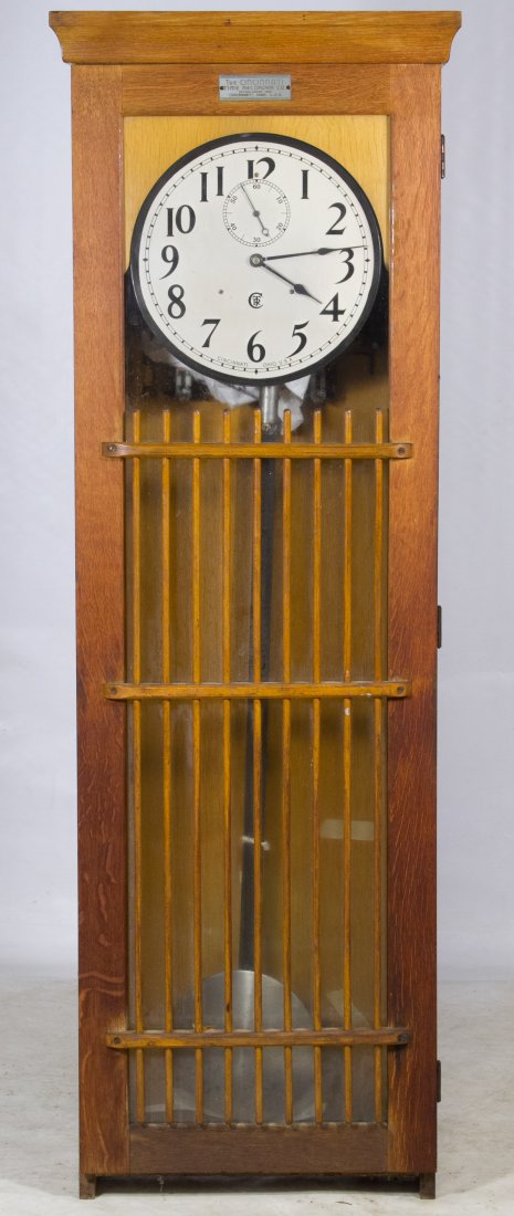 Mission Style Oak Tall Case Clock by Time Recorder Co.: Mission Style Oak Tall Case Clock by Time Recorder Co. Having a metal dial, glass front door with grid-like posts and electrical wiring at back with a Westinghouse motor; can be wall mounted Height: 6