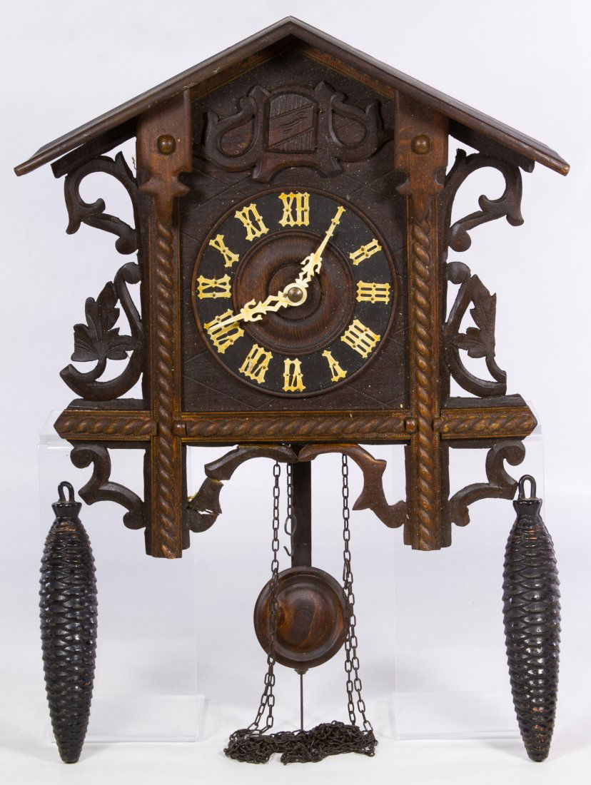 West German Cuckoo Clock: West German Cuckoo Clock Having a wood face, carved foliage frame, two weights, a pendulum and 'West Germany' mark on the two bellows Height: 14.50 inches Category: Decorative Arts > Clocks Shipping S