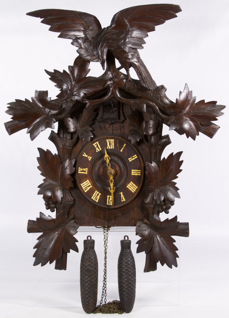 Black Forest Style Cuckoo Clock: Black Forest Style Cuckoo Clock Having an eagle crest, carved leaf frame around the wood clock face; including two weights; also having a partial paper label en verso with a Chicago address Height: 21