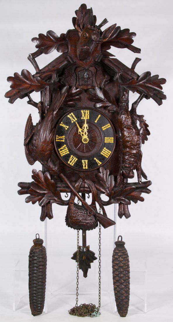 German Black Forest Cuckoo Clock: German Black Forest Cuckoo Clock Having a a stag crest, a carved rabbit, bird, rifle and hunt bag around the clock face and 'West Germany' marked bellows en verso; including weights and pendulum Heigh