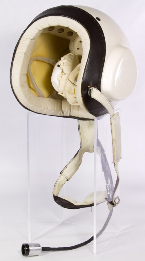 Military Pilot's Helmet: Military Pilot's Helmet Having the mark 'OTK - III 93' on a canvas strap, ear phones inside the hard shell helmet lined with leather, a chin strap with possible built in microphones, an attached plug 