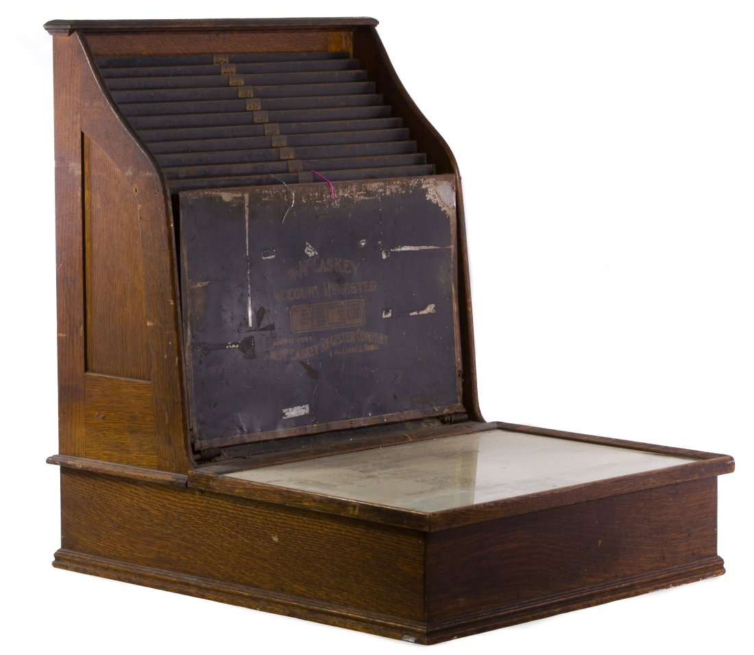 Oak Accounts Register by McCaskey: Oak Accounts Register by McCaskey 1907 oak frame counter top accounts register with stamped tin slots to hold receipts in the spring loaded wire clips, a pencil inscribed paper insert and three wood c