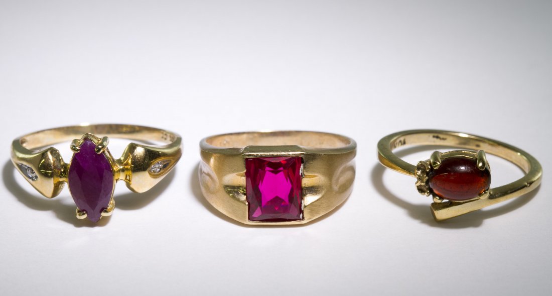 10k Gold, Ruby and Garnet Rings: 10k Gold, Ruby and Garnet Rings Three rings, one having a rectangular cut ruby in a brushed finish band, another having a marquis cut ruby and the third having a horizontally set oval cut cabochon gar