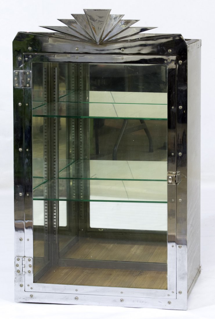 Art Deco Chrome and Glass Display Cabinet: Art Deco Chrome and Glass Display Cabinet Having an abstract sunburst motif on the chrome crest, two glass shelves inside, glass on the sides and top with a solid metal backing Height: 42.00 inches, W