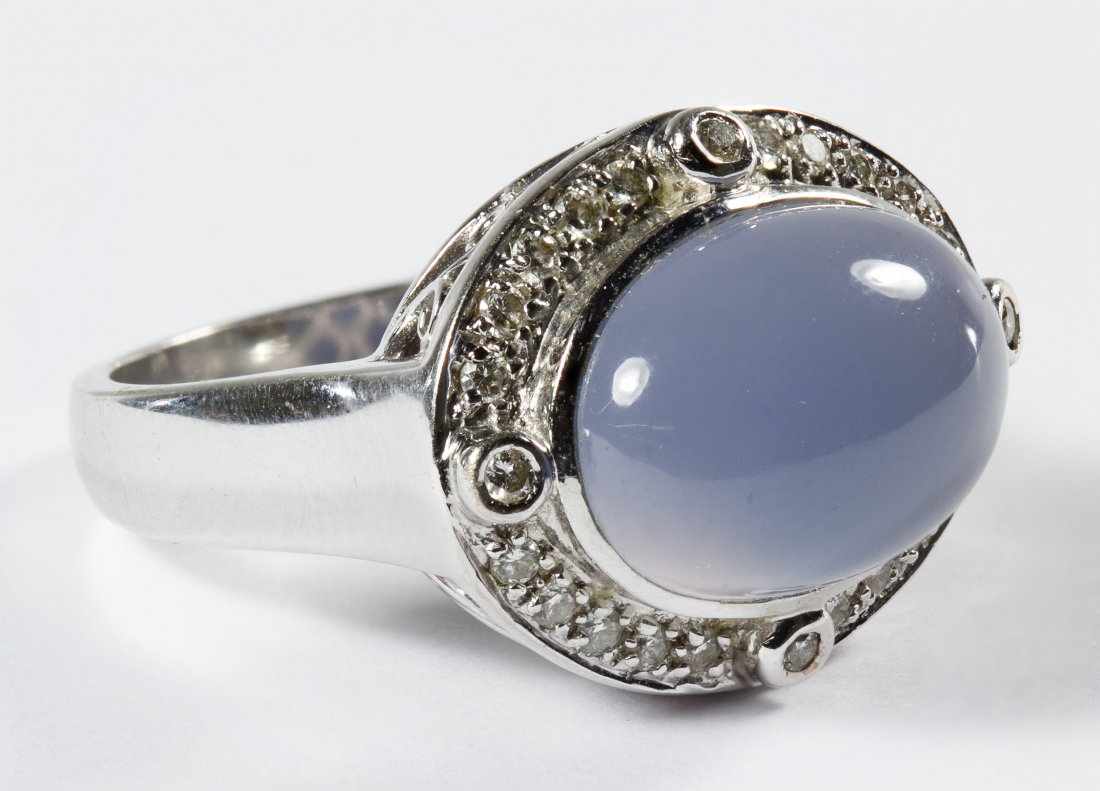 14k White Gold, Moonstone and Diamond Ring: 14k White Gold, Moonstone and Diamond Ring Having an oval cut horizontal set cabochon pale lilac moonstone surrounded by diamond chips; marked 14kw inside band Size: 7 Weight: 4.85 dwts. (total weight