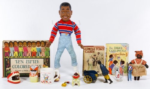Black Americana Toy Assortment: Black Americana Toy Assortment Including a tin wind-up push cart toy, a cloth Mammy doll, children's books, a lead figure and an Urkel talking doll; together with ceramic mugs and a glass Height: 17.0