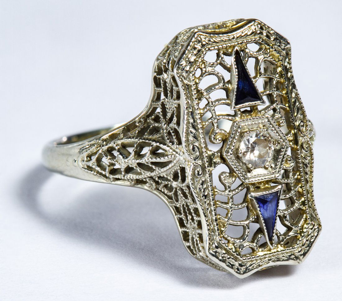 18k White Gold, Spinel and Diamond Ring: 18k White Gold, Spinel and Diamond Ring Art Deco filigree setting having a central diamond flanked by two elongated trillion cut spinels Size: 6.75 Weight: 2.07 dwts. (total weight) Category: Jewelry