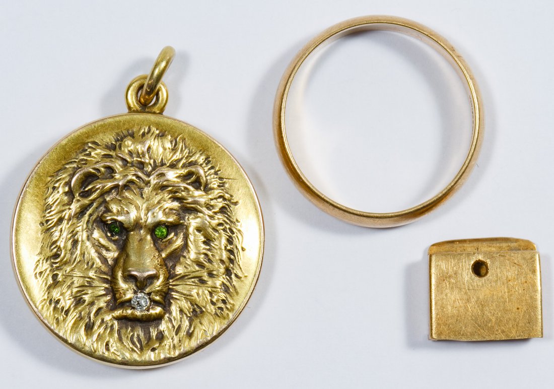 14k Gold Jewelry Assortment: 14k Gold Jewelry Assortment Including a band ring, a lion locket having a round cut diamond with green glass eyes and a piece of scrap gold Diameter: 1.00 inches (locket) Size: 10.5 Weight: 10.58 dwts
