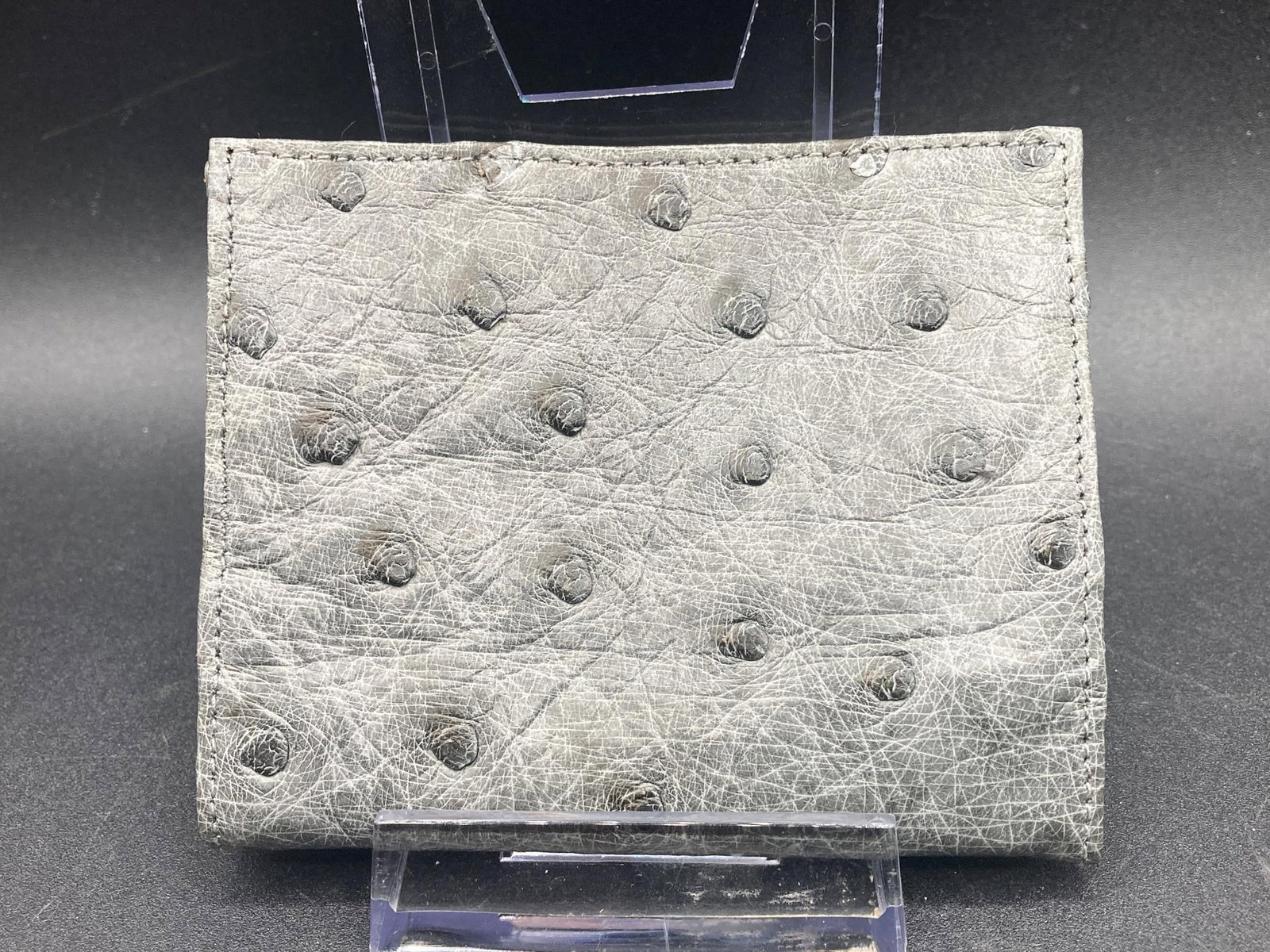 Genuine Ostrich Leather Bifold Wallet: Genuine ostrich leather bifold wallet. Wallet features three card slots, one inner pocket and one inner zippered pocket. Wallet is gray color and measures 4" long. Excellent condition.