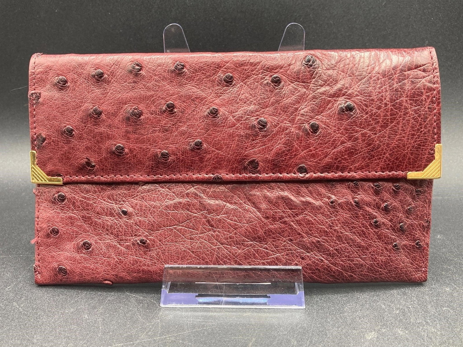 Genuine Ostrich Leather Wallet: Genuine ostrich leather wallet. Features three large inner compartments, snap closure and one exterior zipper pocket. Mahogany color, measures 7" long. Good condition.Measurements: 4" W, 7" L, 1" H