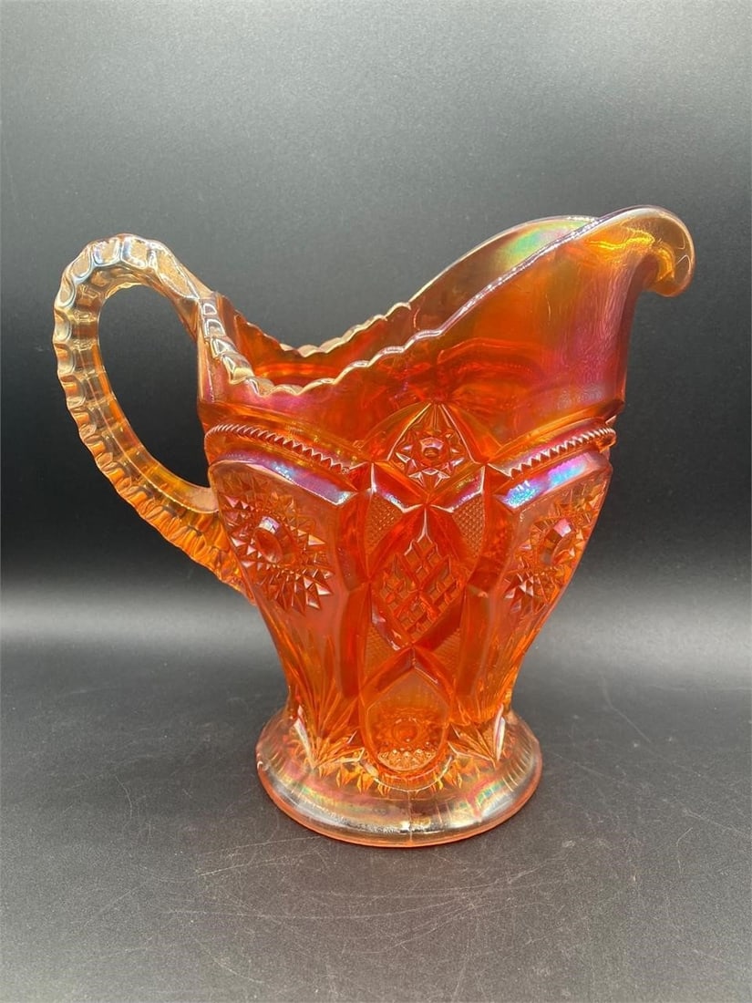 Carnival Glass Marigold Hobstar Pitcher: Carnival glass iridescent marigold hobstar pitcher. Features heirloom and hobstar patterns on glass that changes hue under different lighting. One visible crack on inside of pitcher near bottom, does 