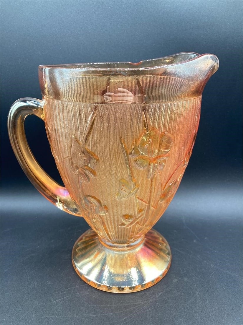 Carnival Glass Marigold Herringbone & Lily Pitcher: Carnival glass iridescent marigold herringbone & lilies pitcher. Feature's herringbone pattern work with lily flower designs on glass that changes hue under different lighting. Measures 9" tall. One c
