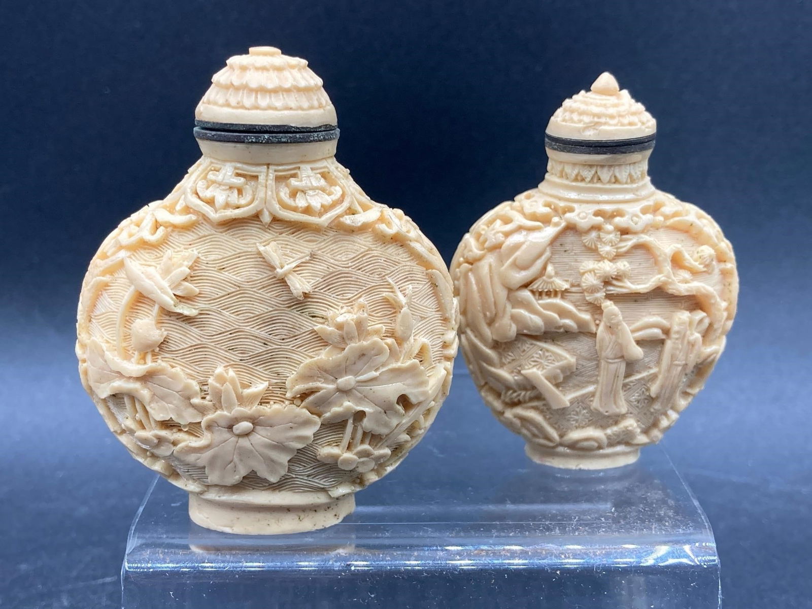 Chinese Carved Bone Snuff Bottles: Pair of vintage Chinese carved bone snuff bottles. Features hand carved designs of traditional wildlife, flowers, people scenes and ornate accents. Larger bottle measures 2". Some small chips, otherwi